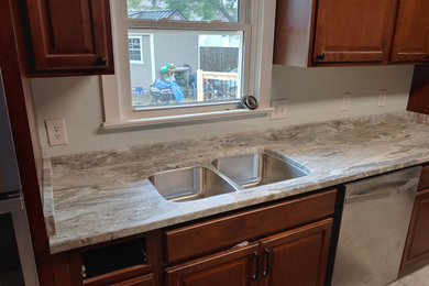 Inspiration for an eat-in kitchen remodel in Other with an undermount sink, brown cabinets, granite countertops, gray backsplash, granite backsplash, stainless steel appliances, no island and gray countertops