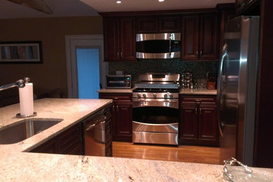 Mid-sized trendy medium tone wood floor kitchen photo in Boston with an undermount sink, raised-panel cabinets, dark wood cabinets, granite countertops, mosaic tile backsplash, stainless steel appliances and blue backsplash