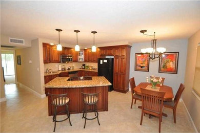 Eat-in kitchen - mid-sized traditional l-shaped ceramic tile eat-in kitchen idea in Miami with a drop-in sink, raised-panel cabinets, medium tone wood cabinets, granite countertops, beige backsplash, black appliances and an island