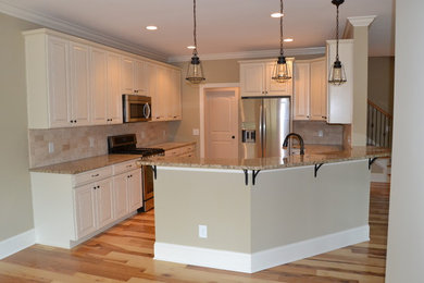 Inspiration for a craftsman light wood floor kitchen remodel in Charlotte with a single-bowl sink, raised-panel cabinets, white cabinets, granite countertops, stone tile backsplash, stainless steel appliances and no island