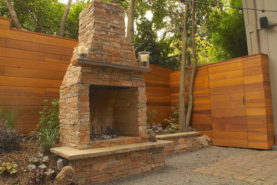 Inspiration for a mid-sized timeless backyard gravel patio remodel in San Francisco with a fireplace and no cover