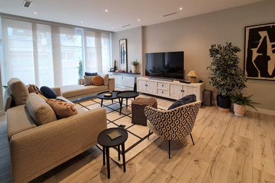 Modelo de salón abierto actual grande con suelo de madera clara, televisor colgado en la pared y alfombra