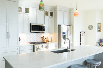 Photo of a small transitional single-wall eat-in kitchen in Milwaukee with a single-bowl sink, shaker cabinets, grey cabinets, quartz benchtops, multi-coloured splashback, glass tile splashback, stainless steel appliances and with island.
