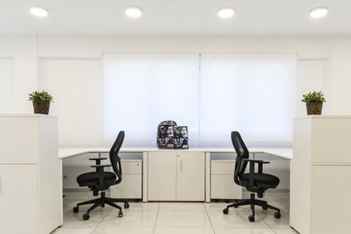 Ejemplo de despacho moderno de tamaño medio con paredes blancas, suelo de baldosas de porcelana y escritorio independiente