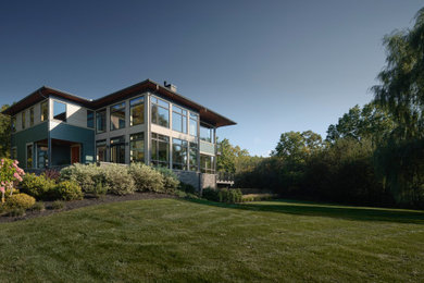 Imagen de fachada de casa verde contemporánea grande de dos plantas con revestimiento de madera, tejado a cuatro aguas y tablilla