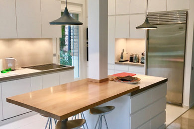 Réalisation d'une très grande cuisine ouverte parallèle minimaliste avec un placard à porte plane, un plan de travail en bois et îlot.