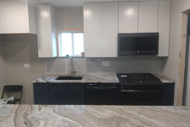 Example of a small trendy galley laminate floor and brown floor eat-in kitchen design in Chicago with an undermount sink, shaker cabinets, blue cabinets, solid surface countertops, white backsplash, subway tile backsplash, black appliances, an island and multicolored countertops