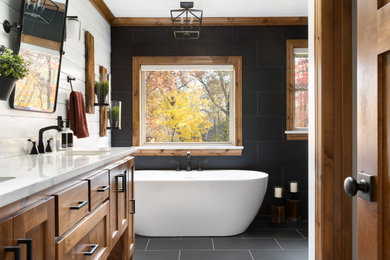 Bathroom - large coastal master black tile and porcelain tile shiplap wall, porcelain tile, black floor, double-sink and vaulted ceiling bathroom idea in Minneapolis with recessed-panel cabinets, brown cabinets, an undermount sink, quartz countertops, a hinged shower door, white countertops and a built-in vanity