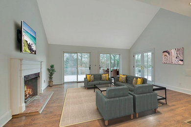 Photo of a contemporary living room in New York with medium hardwood floors, a standard fireplace, a brick fireplace surround and a wall-mounted tv.