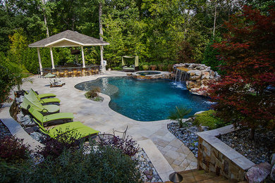 Photo of a large eclectic backyard custom-shaped natural pool in Raleigh with a water feature and natural stone pavers.