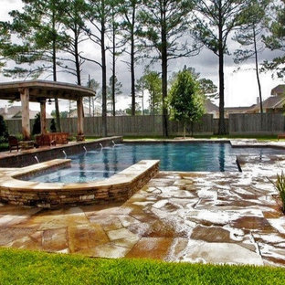 Modern inredning av en stor rektangulär pool på baksidan av huset, med en fontän och stämplad betong