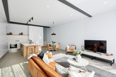 This is an example of a small contemporary open concept living room in Sydney with white walls, concrete floors, a standard fireplace, a brick fireplace surround, a freestanding tv and grey floor.