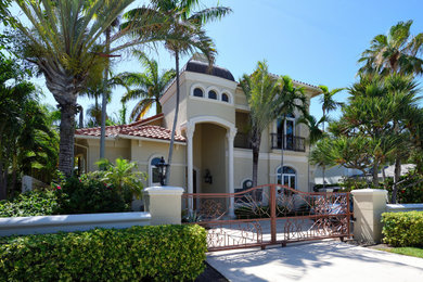 Diseño de fachada de casa beige y marrón mediterránea grande de dos plantas con revestimiento de estuco y tejado de teja de barro