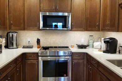 Example of a small transitional u-shaped porcelain tile and beige floor kitchen design in Tampa with an undermount sink, medium tone wood cabinets, stainless steel appliances and no island