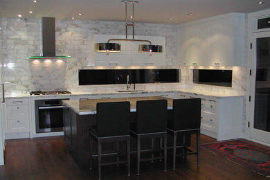 Example of a large minimalist u-shaped medium tone wood floor open concept kitchen design in Calgary with an undermount sink, recessed-panel cabinets, white cabinets, marble countertops, white backsplash, subway tile backsplash, stainless steel appliances and an island