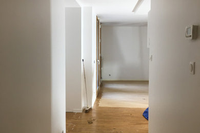 Inspiration pour un couloir design avec un mur blanc et parquet clair.