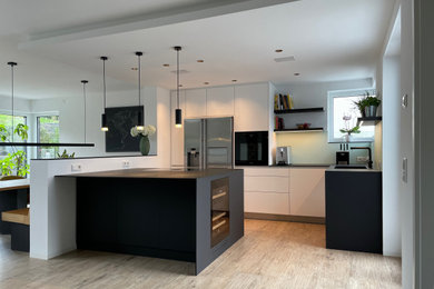 ケルンにある高級な広いコンテンポラリースタイルのおしゃれなキッチン (セラミックタイルの床、ベージュの床、アンダーカウンターシンク、フラットパネル扉のキャビネット、白いキャビネット、ラミネートカウンター、緑のキッチンパネル、ガラス板のキッチンパネル、シルバーの調理設備、黒いキッチンカウンター) の写真