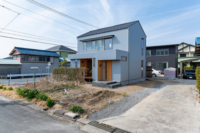Foto de fachada de casa gris y gris de tamaño medio de dos plantas con revestimiento de metal, tejado a dos aguas, tejado de metal y panel y listón
