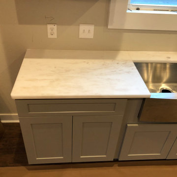 White Rhino Marble Countertops with blue shaker style cabinets.