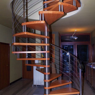 Escalier à colimaçon en inox avec marches en doussié massif, garde-corps en inox