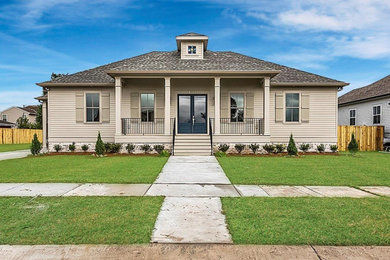 Example of a large classic beige one-story concrete fiberboard house exterior design in New Orleans with a hip roof and a shingle roof