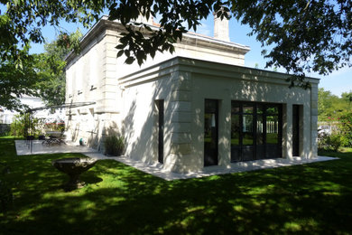 Réalisation d'une façade de maison beige tradition en pierre de taille moyenne avec un toit plat et un toit noir.