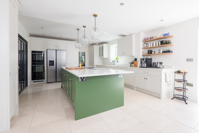 Photo of a large traditional l-shaped open plan kitchen in Other with a belfast sink, shaker cabinets, green cabinets, quartz worktops, stainless steel appliances, porcelain flooring, an island, beige floors, white worktops and feature lighting.