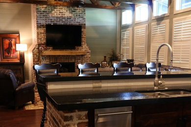 Example of a large urban open concept medium tone wood floor family room design in Houston with green walls, a standard fireplace, a brick fireplace and a wall-mounted tv