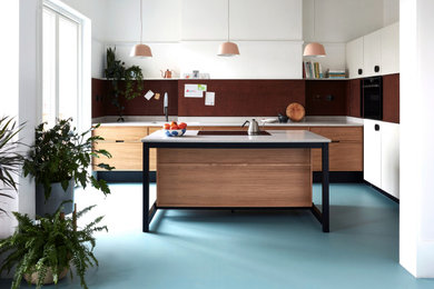 Example of a mid-sized trendy l-shaped vinyl floor and blue floor eat-in kitchen design in Other with a drop-in sink, flat-panel cabinets, medium tone wood cabinets, quartzite countertops, brown backsplash, wood backsplash, black appliances, an island and gray countertops