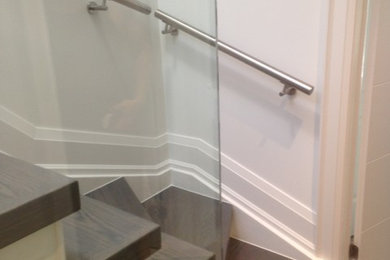 Foto de escalera en L moderna de tamaño medio con escalones de madera y contrahuellas de vidrio