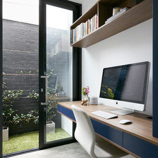 Inspiration for a contemporary study room in Melbourne with white walls, concrete floors and a built-in desk.