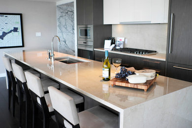Mid-sized minimalist single-wall dark wood floor and brown floor eat-in kitchen photo in Vancouver with an undermount sink, flat-panel cabinets, gray cabinets, marble countertops, beige backsplash, marble backsplash, stainless steel appliances and an island