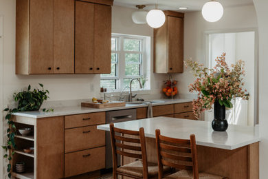 Example of a mid-sized 1950s l-shaped medium tone wood floor kitchen pantry design in Detroit with an undermount sink, flat-panel cabinets, light wood cabinets, quartz countertops, white backsplash, quartz backsplash, stainless steel appliances, a peninsula and white countertops