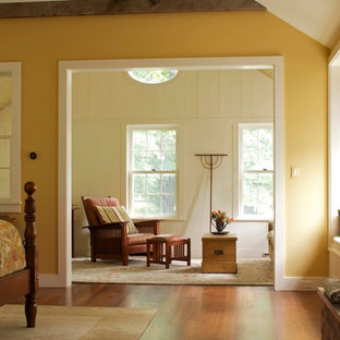 Idée de décoration pour une grande chambre parentale champêtre avec un mur jaune, un sol en bois brun, une cheminée standard et un manteau de cheminée en brique.