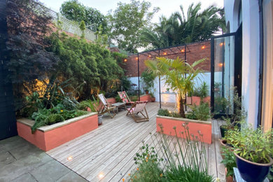 This is an example of a medium sized contemporary courtyard formal full sun garden for summer in Devon with a raised bed and decking.