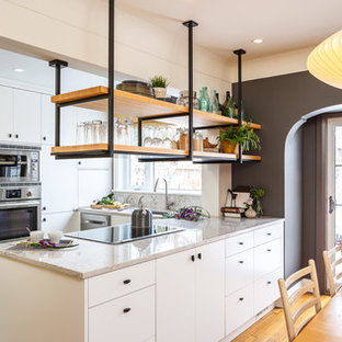 Выдающиеся фото от архитекторов и дизайнеров интерьера: маленькая п-образная кухня в стиле лофт с плоскими фасадами, белыми фасадами, столешницей из гранита, белым фартуком, техникой из нержавеющей стали, островом, обеденным столом, врезной раковиной, фартуком из каменной плиты, полом из сланца и серым полом