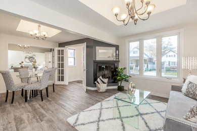 Example of a mid-sized trendy open concept medium tone wood floor and beige floor family room design in Toronto with beige walls, a corner fireplace, a stone fireplace and no tv