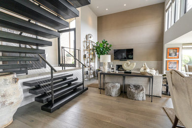Example of a large minimalist open concept light wood floor and beige floor living room design in Orange County with white walls, a standard fireplace, a stone fireplace and a wall-mounted tv