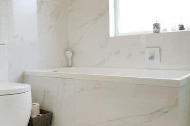 Design ideas for a large contemporary family bathroom in London with glass-front cabinets, white cabinets, a built-in bath, a corner shower, a two-piece toilet, white tiles, porcelain tiles, white walls, porcelain flooring, a submerged sink, marble worktops, white floors and a sliding door.