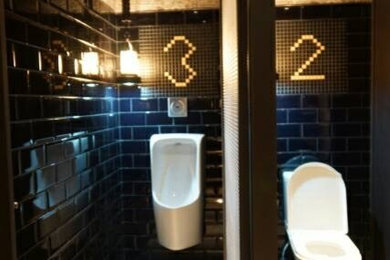 Urban black tile and ceramic tile bathroom photo in Other with dark wood cabinets, tile countertops, a two-piece toilet and black walls