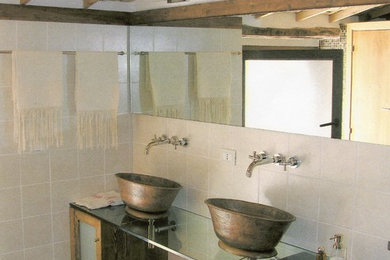 Ispirazione per un bagno di servizio mediterraneo con lavabo a bacinella e top in vetro