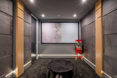 Mid-sized minimalist enclosed carpeted and black floor home theater photo in Los Angeles with gray walls and a projector screen