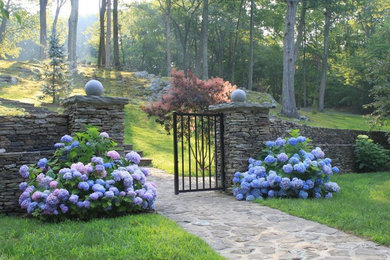 This is an example of a medium sized classic back formal partial sun garden in Bridgeport with a retaining wall and natural stone paving.