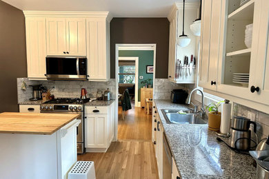 Ejemplo de cocina comedor de estilo de casa de campo con puertas de armario blancas, salpicadero multicolor, electrodomésticos de acero inoxidable y una isla