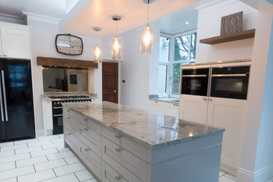 This is an example of a large classic kitchen in Manchester with shaker cabinets, white cabinets, granite worktops, mirror splashback, stainless steel appliances, terracotta flooring, an island and white floors.