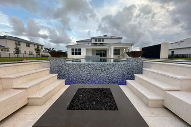 Large minimalist backyard stone and rectangular pool photo in Miami