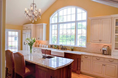 Example of a large transitional galley light wood floor and beige floor open concept kitchen design in Philadelphia with a farmhouse sink, raised-panel cabinets, white cabinets, granite countertops, white backsplash, subway tile backsplash, paneled appliances and two islands