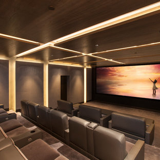 Large contemporary enclosed home cinema in Los Angeles with carpet, a projector screen, grey walls and grey floors.