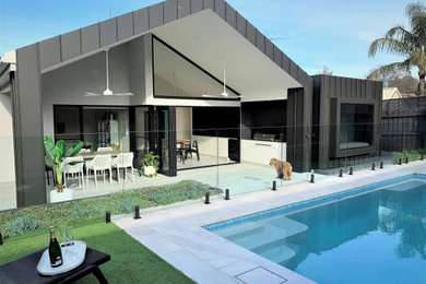 This is an example of a contemporary one-storey grey house exterior in Melbourne with a gable roof and a metal roof.