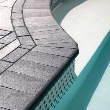 Traditional poolside paradise with grey and black pavers